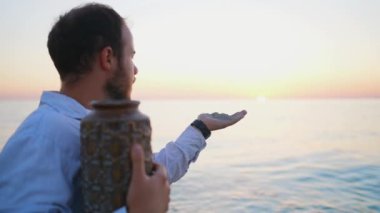 İnsan avucunun içinden külleri yakma vazosunun külleriyle savurur. Külleri suyun üzerine serpme töreni.