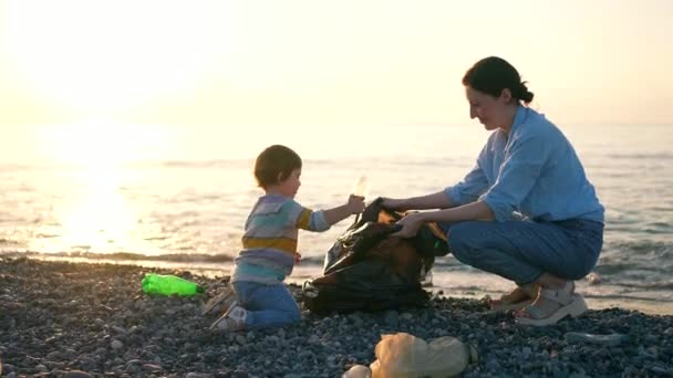 Мать Маленькая Дочь Добровольцы Собирают Пластиковый Мусор Океан Пляж Закат — стоковое видео