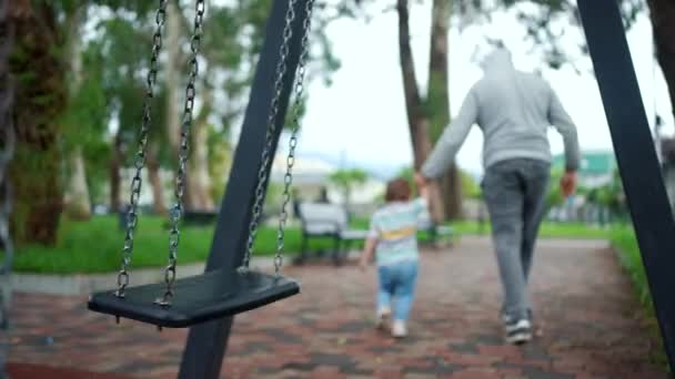 Entführer Und Ein Kind Auf Dem Spielplatz Vor Einer Schaukel — Stockvideo