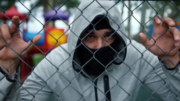 Verbrecher Mit Maske Und Kapuze Auf Dem Spielplatz Beobachtet Aus — Stockvideo