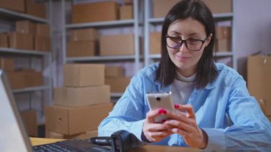 Pozitif genç bir bayan çalışanın portresi. Elinde telefonu, yakından gülümsüyor.