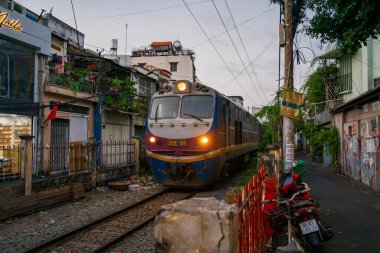 Ho Chi Minh, Viet Nam - 8 Nisan 2023: Dar bir sokaktan geçen trenin inanılmaz manzarası, Hanoi Eski Mahallesi. Trenin fotoğraflarını çeken turistler. Hanoi Tren Sokağı popüler bir yerdir.