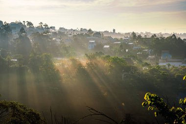 Altın ışıklar dağlara doğru parlıyor. Vadinin üzerine güneş ışınları. Tepenin üzerinden güneş ışınları. Dağlardaki bulutlardan gelen ışık huzmesi. Güneş ışınları dağların arasından geçiyor. Bao Loc, Vietnam