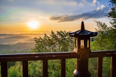 Linh Quy Phap An Tapınağı, Bao Loc, Vietnam 'da sabah sisi boyunca görülebilir siluetleri olan dağ siluetleri. Turuncu gökyüzü arka planı. Yumuşak odak