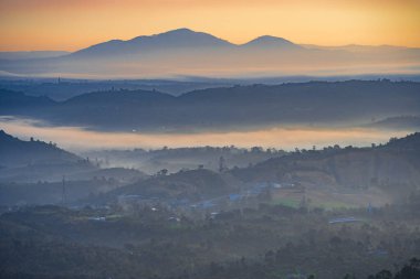 Linh Quy Phap An Tapınağı, Bao Loc, Vietnam 'da sabah sisi boyunca görülebilir siluetleri olan dağ siluetleri. Turuncu gökyüzü arka planı. Yumuşak odak