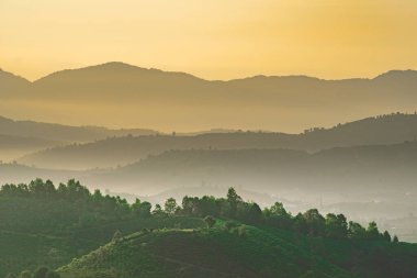 Linh Quy Phap An Tapınağı, Bao Loc, Vietnam 'da sabah sisi boyunca görülebilir siluetleri olan dağ siluetleri. Turuncu gökyüzü arka planı. Yumuşak odak