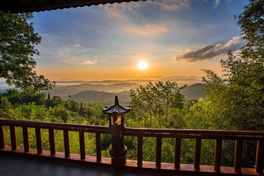 Linh Quy Phap An Tapınağı, Bao Loc, Vietnam 'da sabah sisi boyunca görülebilir siluetleri olan dağ siluetleri. Turuncu gökyüzü arka planı. Yumuşak odak
