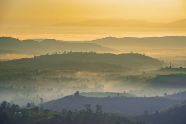 Linh Quy Phap An Tapınağı, Bao Loc, Vietnam 'da sabah sisi boyunca görülebilir siluetleri olan dağ siluetleri. Turuncu gökyüzü arka planı. Yumuşak odak