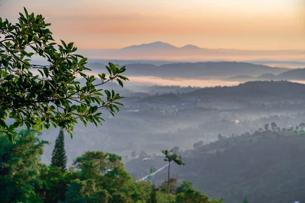 stock image Mountain range with visible silhouettes through the morning colorful fog at Linh Quy Phap An temple, Bao Loc, Vietnam. Orange sky background. Soft focus