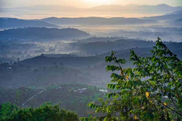 stock image Mountain range with visible silhouettes through the morning colorful fog at Linh Quy Phap An temple, Bao Loc, Vietnam. Orange sky background. Soft focus