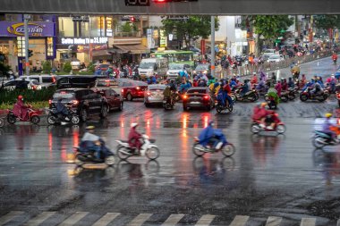 Ho Chi Minh, Viet Nam - 24 Nisan 2023: Vietnamlı taçlandırılmış insanlar yoğun yağmur ve trafik sıkışıklığında kask ve yağmurluk giyerler. Saygon, Vietnam 'da yağmur mevsimi.