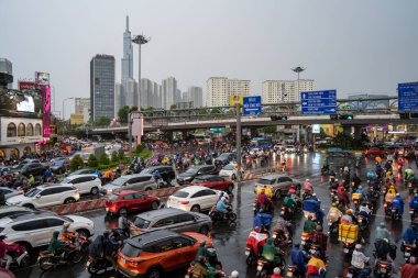 Ho Chi Minh, Viet Nam - 24 Nisan 2023: Vietnamlı taçlandırılmış insanlar yoğun yağmur ve trafik sıkışıklığında kask ve yağmurluk giyerler. Saygon, Vietnam 'da yağmur mevsimi.