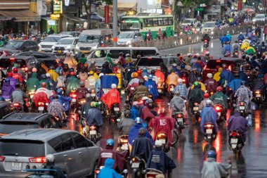 Ho Chi Minh, Viet Nam - 24 Nisan 2023: Vietnamlı taçlandırılmış insanlar yoğun yağmur ve trafik sıkışıklığında kask ve yağmurluk giyerler. Saygon, Vietnam 'da yağmur mevsimi.