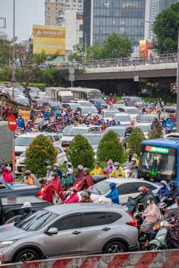 Ho Chi Minh, Viet Nam - 24 Nisan 2023: Vietnamlı taçlandırılmış insanlar yoğun yağmur ve trafik sıkışıklığında kask ve yağmurluk giyerler. Saygon, Vietnam 'da yağmur mevsimi.