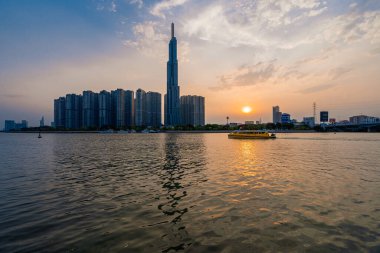 Ho Chi Minh, Viet Nam - 8 Nisan 2023: Landmark 81 'de günbatımı manzarası - Saigon Nehri boyunca uzanan inşaat binaları ile süper uzun bir gökdelen ve Saigon köprüsü