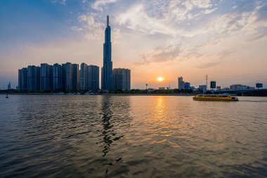Ho Chi Minh, Viet Nam - 8 Nisan 2023: Landmark 81 'de günbatımı manzarası - Saigon Nehri boyunca uzanan inşaat binaları ile süper uzun bir gökdelen ve Saigon köprüsü