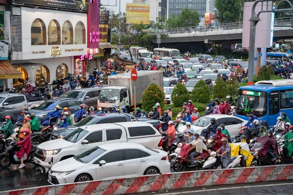 stock image Ho Chi Minh, Viet Nam - 24 April 2023: Vietnamese crowned people wear helmet and raincoat ride motorbike in heavy rain and traffic jam. This time is rainy season at Saigon, Vietnam