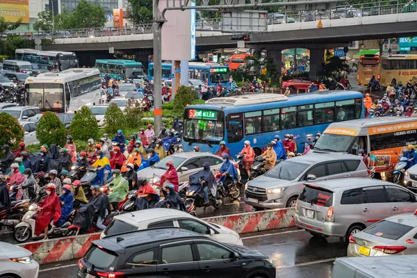 stock image Ho Chi Minh, Viet Nam - 24 April 2023: Vietnamese crowned people wear helmet and raincoat ride motorbike in heavy rain and traffic jam. This time is rainy season at Saigon, Vietnam