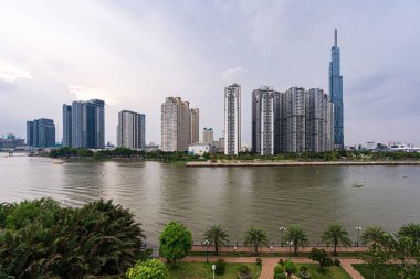 Ho Chi Minh, Viet Nam - 28 Nisan 2023: Landmark 81 'de günbatımı manzarası - Saigon Nehri boyunca uzanan inşaat binaları ile süper uzun bir gökdelen ve Saigon köprüsü