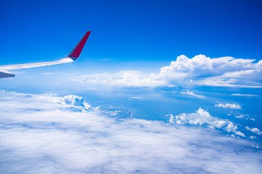 Mavi gökyüzü ve beyaz bulutlu uçak penceresinden bak. Kırmızı uç