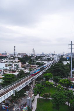 Ho Chi Minh, Vietnam - 21 Ağustos 2023: Yük treni şehrin dar sokaklarından geçiyor. Yağmurlu bir öğleden sonra Saigon 'a giden tren