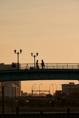 Ho Chi Minh City, Viet Nam 30 Aralık 2023, akşam köprüde el ele tutuşan romantik bir çiftin silueti. Güzel gökyüzü