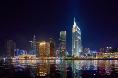 Ho Chi Minh, Viet Nam - 31 DEC 2023: Ho Chi Minh City silueti ve Saigon Nehri. Şehir merkezindeki gökdelen ve diğer modern binaların inanılmaz renkli gece manzarası. Seyahat kavramı