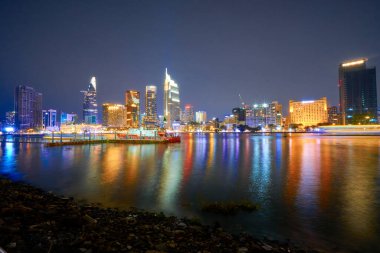 Ho Chi Minh, Viet Nam - 20 Ocak 2024: Ho Chi Minh City silueti ve Saigon Nehri. Şehir merkezindeki gökdelen ve diğer modern binaların inanılmaz renkli gece manzarası. Seyahat kavramı