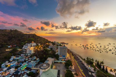 Vung Tau, VIETNAM 3 Mayıs 2024: Güzel günbatımı ve tekneleri olan üst manzara. Vung Tau 'nun yukarıdan panoramik manzarası dalgalar, sahil, sokaklar, hindistan cevizi ağaçları ve Vietnam' daki Tao Phung dağları.