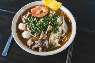 Tom Yum çorbası - Vietnam 'da tahta masada karidesli Tayland çorbası ve pirinç eriştesi
