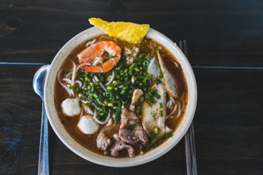 Tom Yum çorbası - Vietnam 'da tahta masada karidesli Tayland çorbası ve pirinç eriştesi