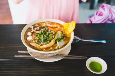 Tom Yum çorbası - Vietnam 'da tahta masada karidesli Tayland çorbası ve pirinç eriştesi