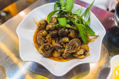 Kızarmış su ıspanağını salyangozla karıştır. Gri arka plandaki deniz ürünleri manzarasında servis edilir.