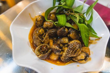 Kızarmış su ıspanağını salyangozla karıştır. Gri arka plandaki deniz ürünleri manzarasında servis edilir.