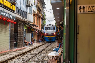 Hanoi, Vietnam - 27 Haziran 2024: Hanoi 'nin Eski Mahallesi' ndeki dar bir sokaktan bir tren geçiyor. Turistler hızlı trenin fotoğraflarını çeker. Hanoi 'nin Tren Sokağı popüler bir turistik merkezdir..