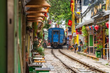 Hanoi, Vietnam - 27 Haziran 2024: Hanoi 'nin Eski Mahallesi' ndeki dar bir sokaktan bir tren geçiyor. Turistler hızlı trenin fotoğraflarını çeker. Hanoi 'nin Tren Sokağı popüler bir turistik merkezdir..