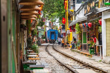 Hanoi, Vietnam - 27 Haziran 2024: Hanoi 'nin Eski Mahallesi' ndeki dar bir sokaktan bir tren geçiyor. Turistler hızlı trenin fotoğraflarını çeker. Hanoi 'nin Tren Sokağı popüler bir turistik merkezdir..