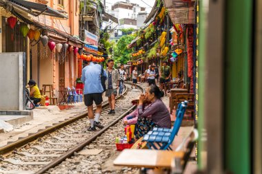 Hanoi, Vietnam - 27 Haziran 2024: Hanoi 'nin Eski Mahallesi' ndeki dar bir sokaktan bir tren geçiyor. Turistler hızlı trenin fotoğraflarını çeker. Hanoi 'nin Tren Sokağı popüler bir turistik merkezdir..