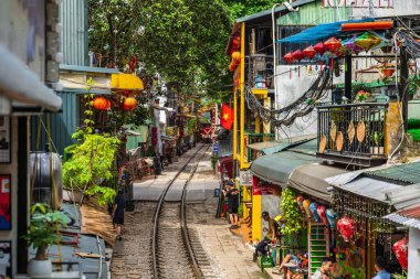 Hanoi, Vietnam - 27 Haziran 2024: Hanoi 'nin Eski Mahallesi' ndeki dar bir sokaktan bir tren geçiyor. Turistler hızlı trenin fotoğraflarını çeker. Hanoi 'nin Tren Sokağı popüler bir turistik merkezdir..