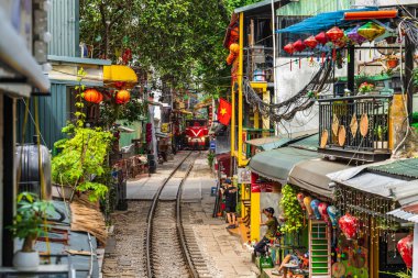 Hanoi, Vietnam - 27 Haziran 2024: Hanoi 'nin Eski Mahallesi' ndeki dar bir sokaktan bir tren geçiyor. Turistler hızlı trenin fotoğraflarını çeker. Hanoi 'nin Tren Sokağı popüler bir turistik merkezdir..