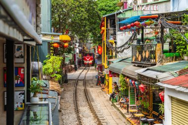 Hanoi, Vietnam - 27 Haziran 2024: Hanoi 'nin Eski Mahallesi' ndeki dar bir sokaktan bir tren geçiyor. Turistler hızlı trenin fotoğraflarını çeker. Hanoi 'nin Tren Sokağı popüler bir turistik merkezdir..