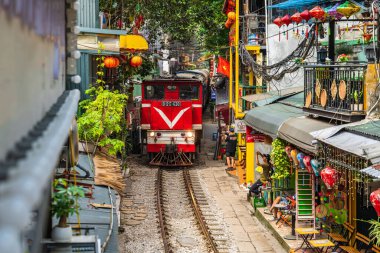 Hanoi, Vietnam - 27 Haziran 2024: Hanoi 'nin Eski Mahallesi' ndeki dar bir sokaktan bir tren geçiyor. Turistler hızlı trenin fotoğraflarını çeker. Hanoi 'nin Tren Sokağı popüler bir turistik merkezdir..