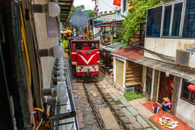 Hanoi, Vietnam - 27 Haziran 2024: Hanoi 'nin Eski Mahallesi' ndeki dar bir sokaktan bir tren geçiyor. Turistler hızlı trenin fotoğraflarını çeker. Hanoi 'nin Tren Sokağı popüler bir turistik merkezdir..