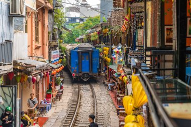 Hanoi, Vietnam - 27 Haziran 2024: Hanoi 'nin Eski Mahallesi' ndeki dar bir sokaktan bir tren geçiyor. Turistler hızlı trenin fotoğraflarını çeker. Hanoi 'nin Tren Sokağı popüler bir turistik merkezdir..