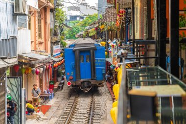 Hanoi, Vietnam - 27 Haziran 2024: Hanoi 'nin Eski Mahallesi' ndeki dar bir sokaktan bir tren geçiyor. Turistler hızlı trenin fotoğraflarını çeker. Hanoi 'nin Tren Sokağı popüler bir turistik merkezdir..