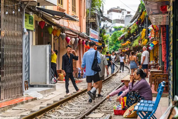 Hanoi, Vietnam - 27 Haziran 2024: Hanoi 'nin Eski Mahallesi' ndeki dar bir sokaktan bir tren geçiyor. Turistler hızlı trenin fotoğraflarını çeker. Hanoi 'nin Tren Sokağı popüler bir turistik merkezdir..