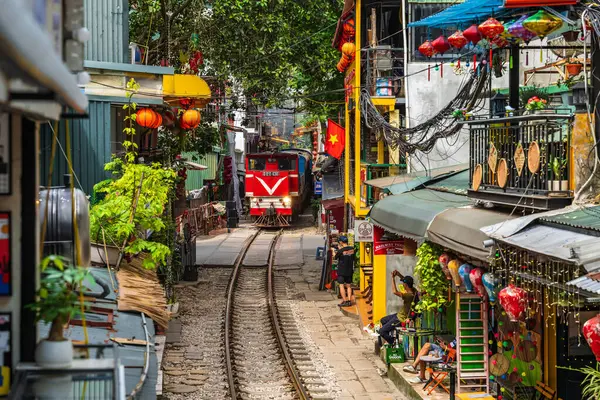 Hanoi, Vietnam - 27 Haziran 2024: Hanoi 'nin Eski Mahallesi' ndeki dar bir sokaktan bir tren geçiyor. Turistler hızlı trenin fotoğraflarını çeker. Hanoi 'nin Tren Sokağı popüler bir turistik merkezdir..
