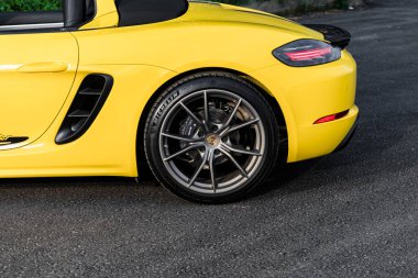 Hanoi, Vietnam - 26 Haziran 2024: Hanoi, Vietnam 'da sokağa park edilmiş sarı bir Porsche 718 Boxster. Porsche, 1931 'de kurulan yüksek performanslı spor arabalar konusunda uzman bir Alman otomobil üreticisi..
