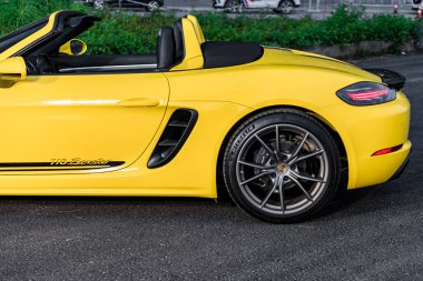 Hanoi, Vietnam - 26 Jun 2024 : A yellow Porsche 718 Boxster parked on the street in Hanoi, Vietnam. Porsche is a German automobile manufacturer specializing in high-performance sports cars founded in 1931. clipart