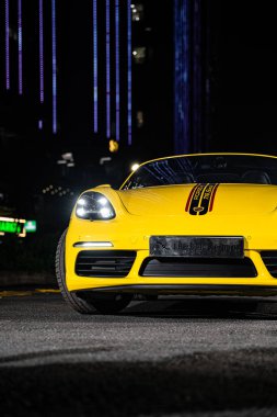 Hanoi, Vietnam - 26 Haziran 2024: Hanoi, Vietnam 'da sokağa park edilmiş sarı bir Porsche 718 Boxster. Porsche, 1931 'de kurulan yüksek performanslı spor arabalar konusunda uzman bir Alman otomobil üreticisi..